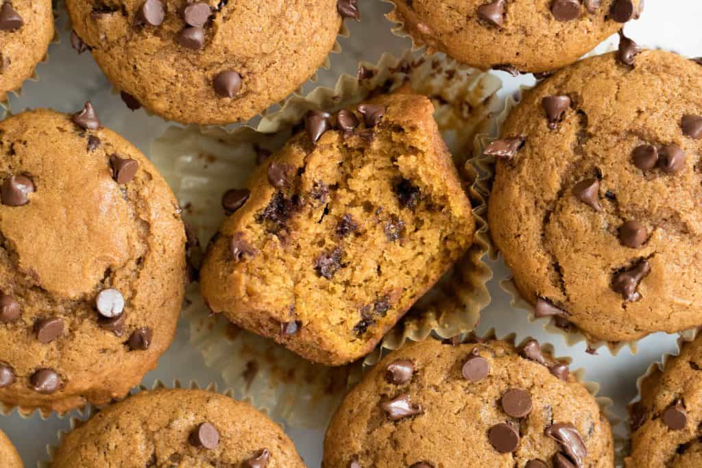 overhead shot of pumpkin chocolate chip muffins with one bit in the muddle