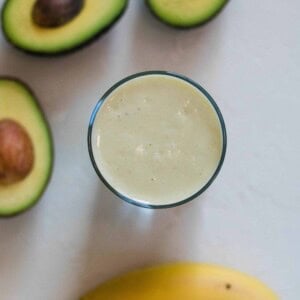 overhead shot of three half avocados, a banana, and the avocado banana smoothie