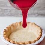 Pie crust filled with cranberry custard before baking