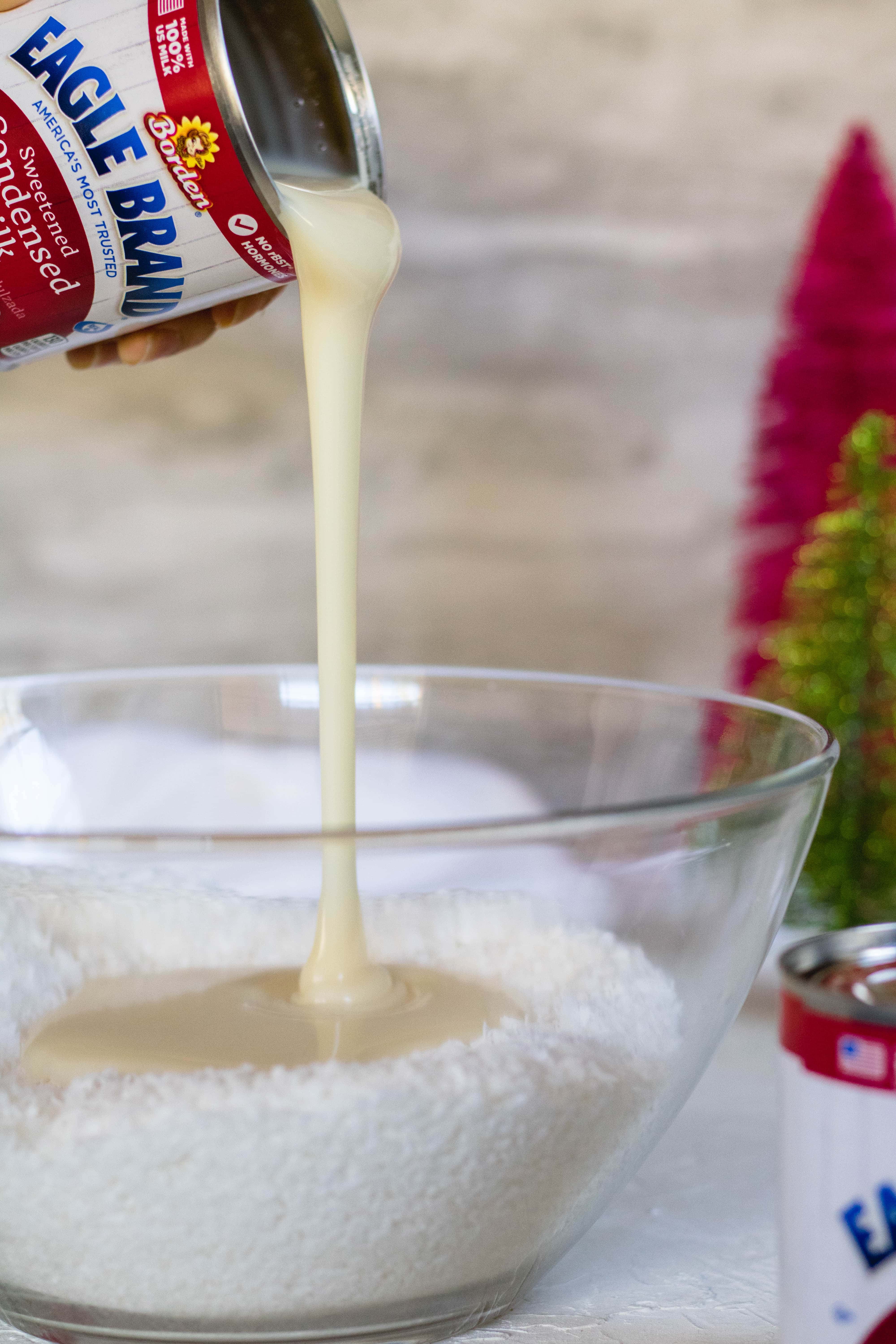 Pouring eagle brand sweetened condensed milk into coconut flakes