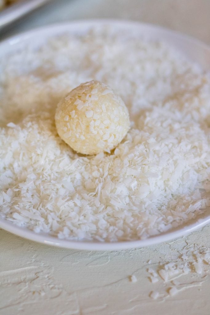 Rolling a treat ball in extra shredded coconut while it is still tacky.