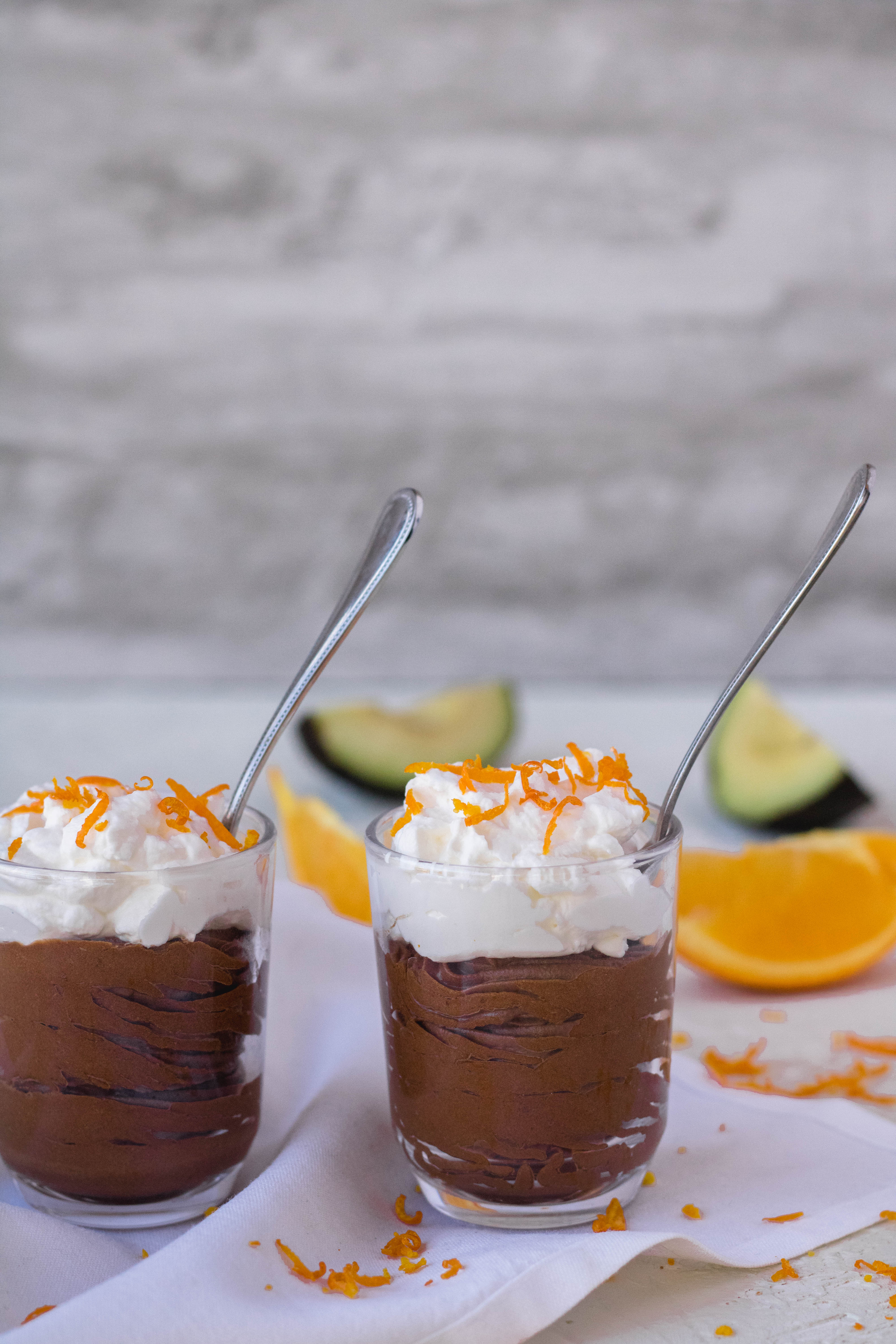 Two vegan avocado chocolate mousse cups with spoons