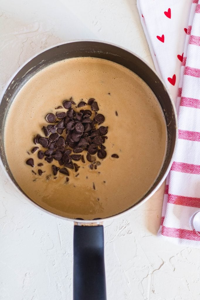 Adding the chocolate chips to the peanut butter and coconut oil