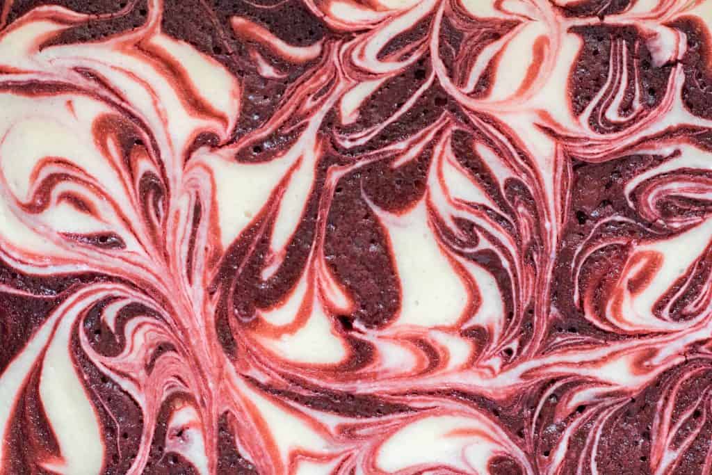 Close up overhead view of cheesecake swirled red velvet brownies showing the beautiful marbled pattern of cream cheese and vibrant red velvet brownie batter