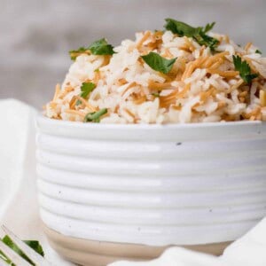Lebanese rice pilaf with toasted vermicelli and parsley piled high in a ribbed white bowl.