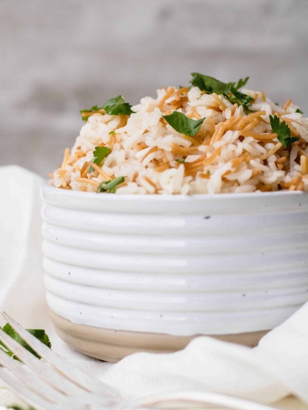 Lebanese rice pilaf with toasted vermicelli and parsley piled high in a ribbed white bowl.