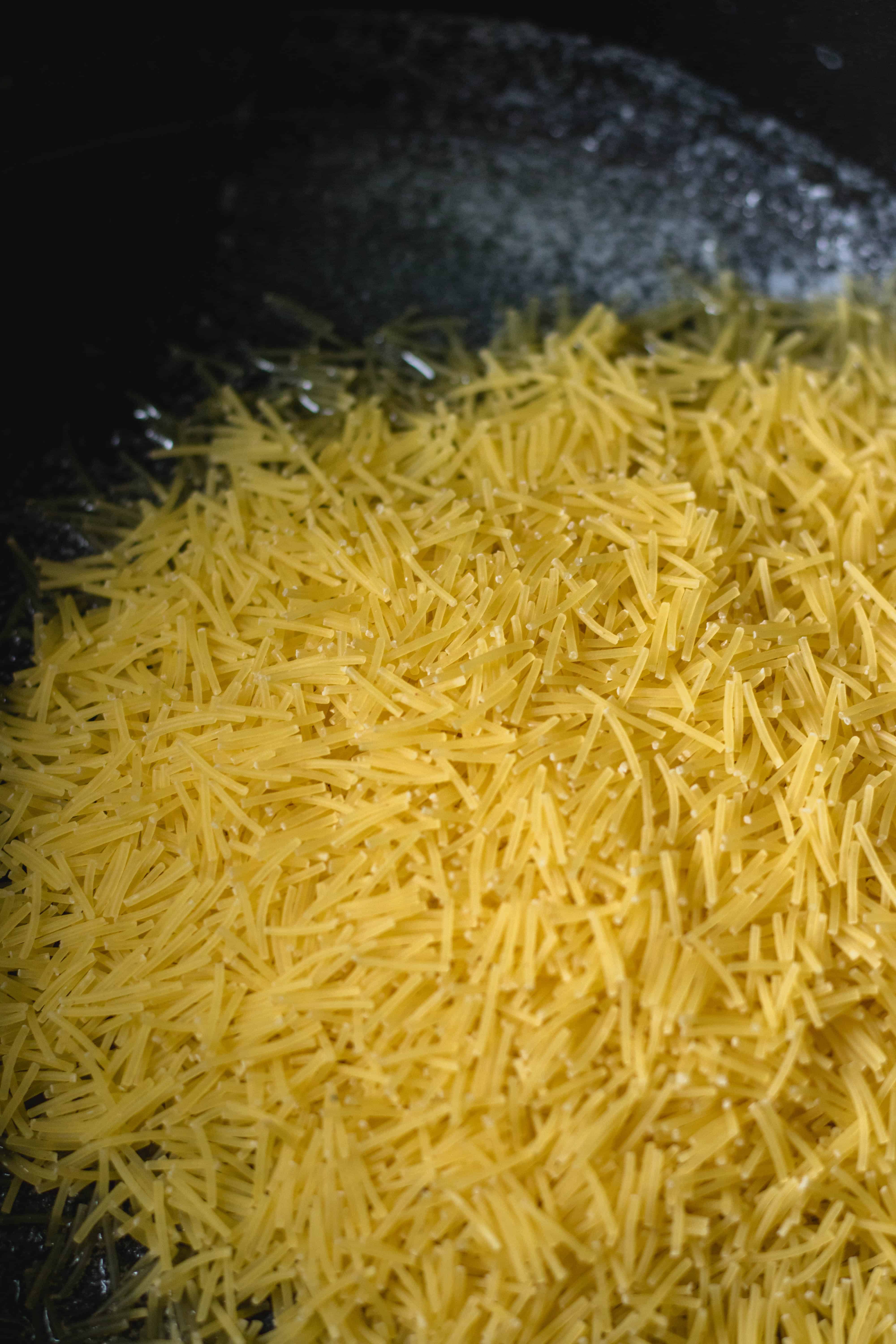 Vermicelli noodles starting to toast in melted butter in a nonstick pan.