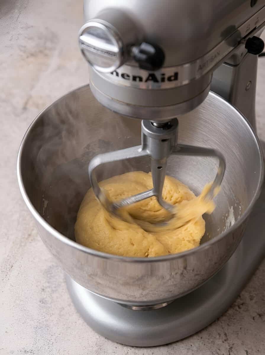 Choux dough beaten in a stand mixer bowl before adding eggs.