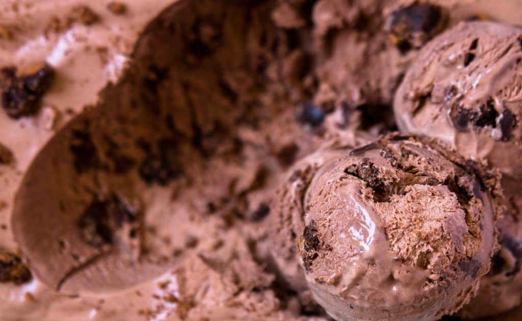 Close up of scoops of chocolate no churn ice cream with brownie chunks mixed throughout showing the creamy texture and brownie pieces