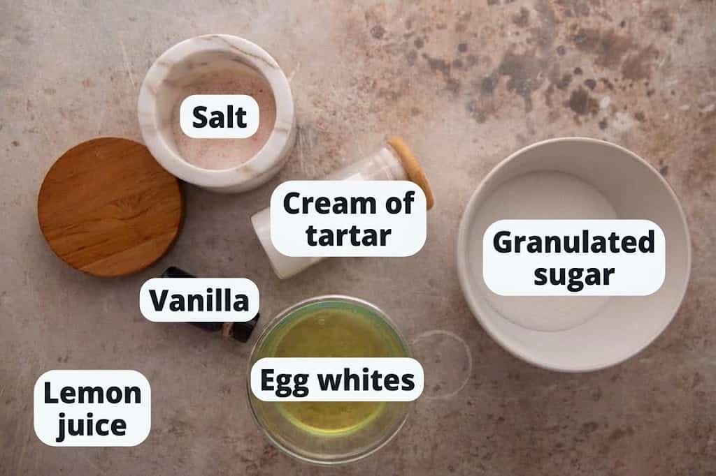 Labeled ingredients for vanilla meringue cookies: egg whites, sugar, cream of tartar, vanilla, and salt.