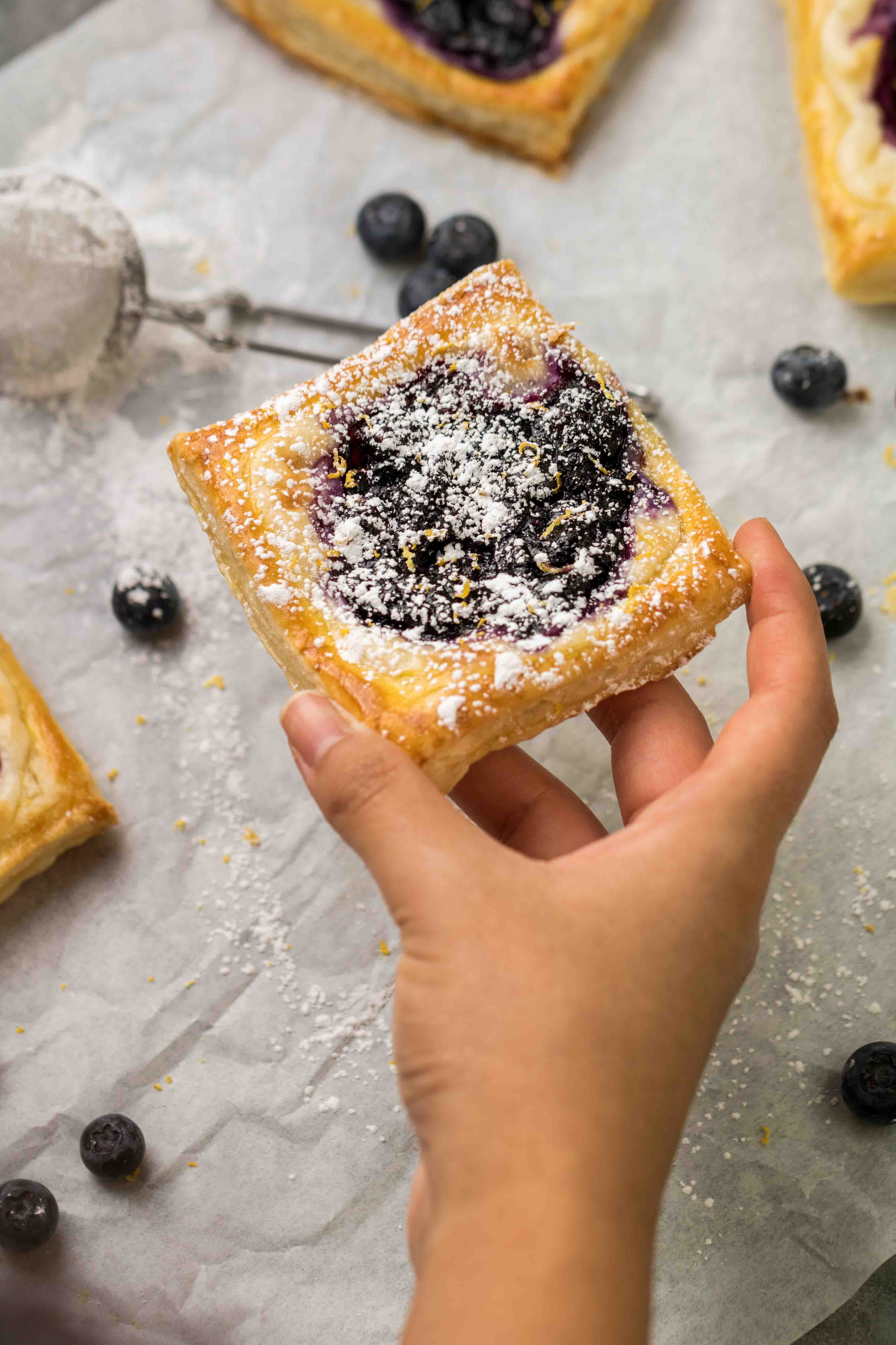 Hand holding blueberry cheese danish made out of puff pastry