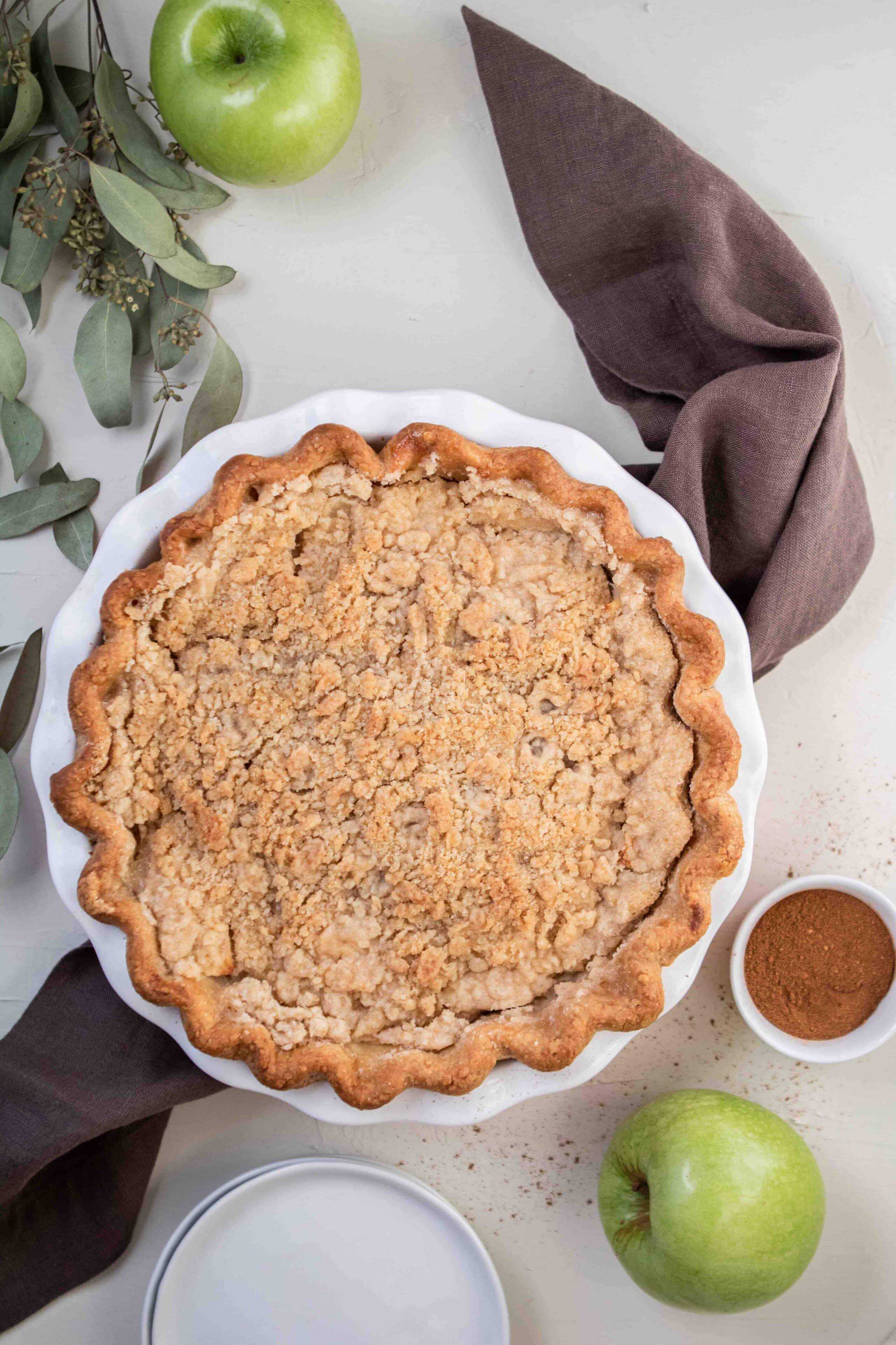 Overhead shot of dutch apple pie with apples on the side