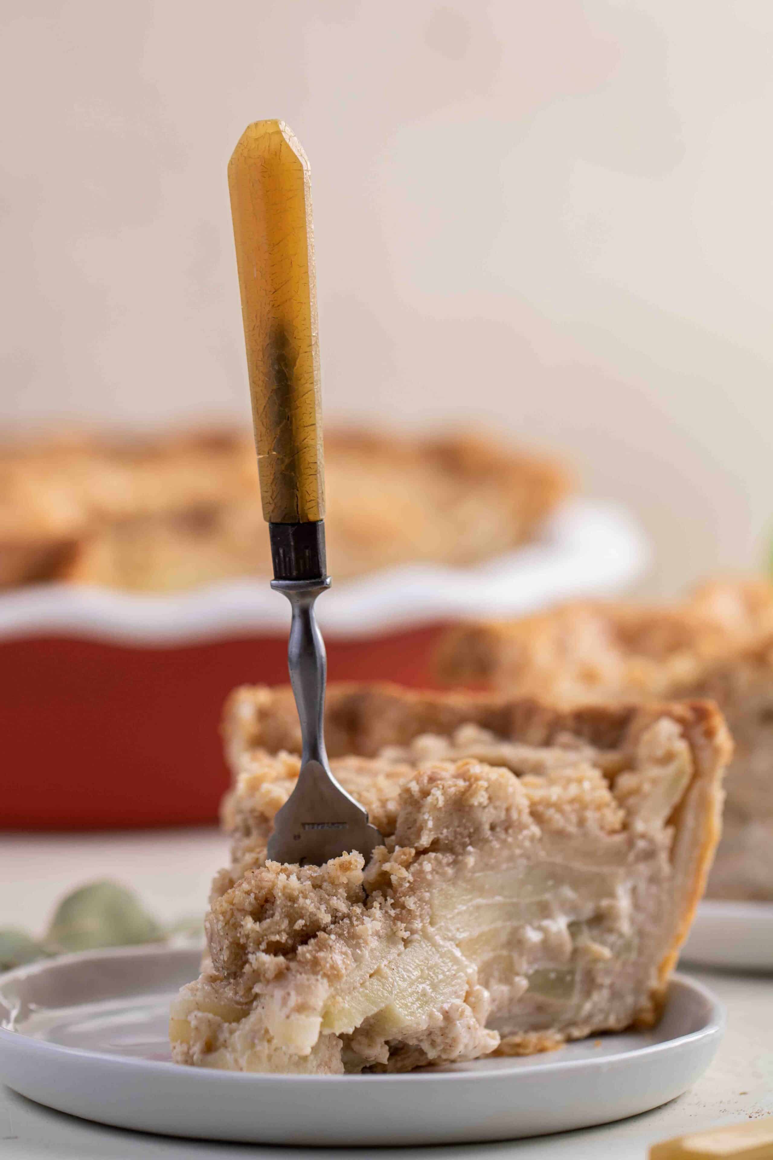 Apple pie slice with a fork inserted in the center