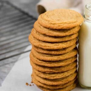 Soft and chewy brown sugar cookies stacked up against a bottle of milk