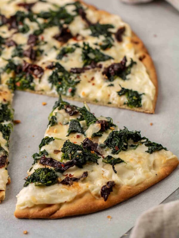 Slice of spinach pizza with white sauce