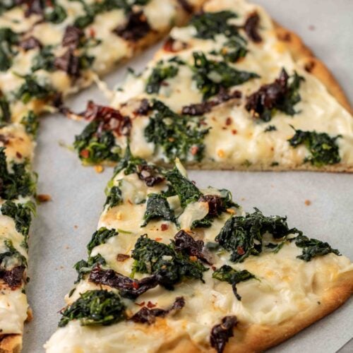 Baked slice of spinach pizza with white sauce