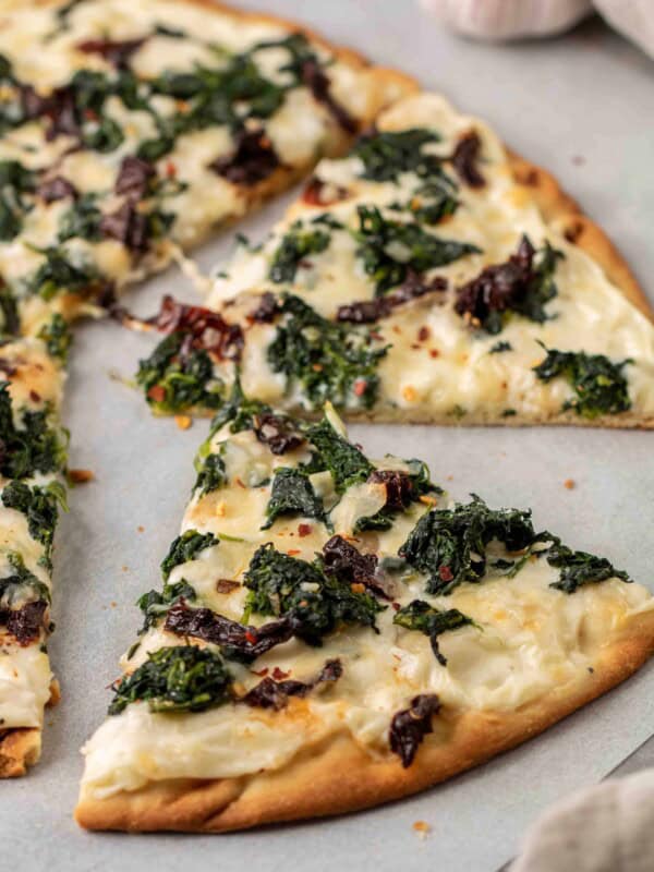 Baked slice of spinach pizza with white sauce