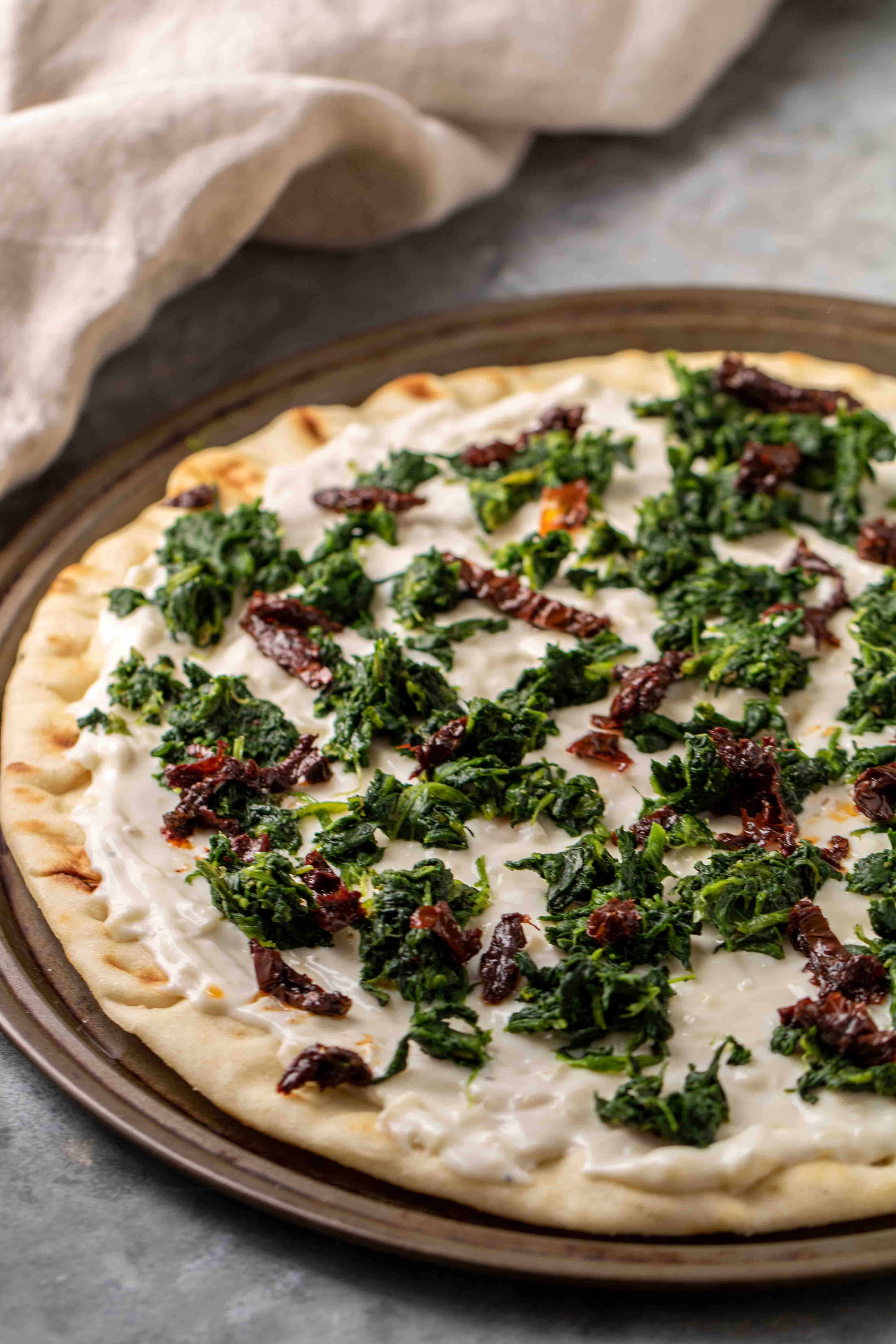 spinach pizza with white sauce before going to the oven