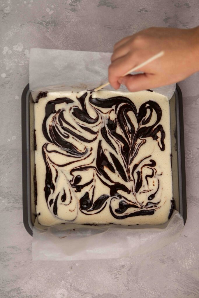Swirling the brownie batter into the cheesecake batter