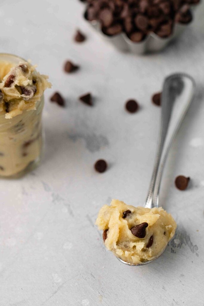 Cookie dough in a spoon next to chocolate chips