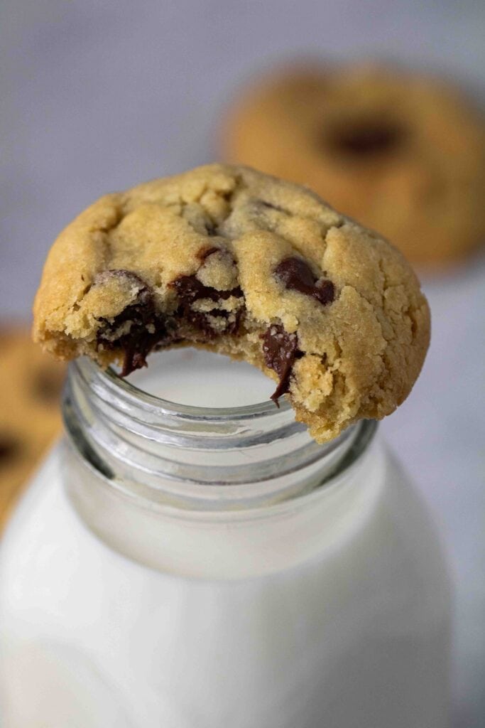 Soft air fryer chocolate chip cookie resting on a glass jar of milk