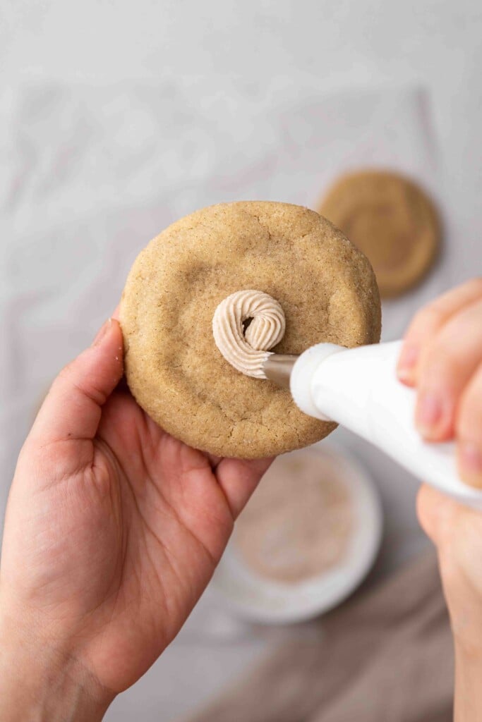 Hand piping buttercream on churro cookie