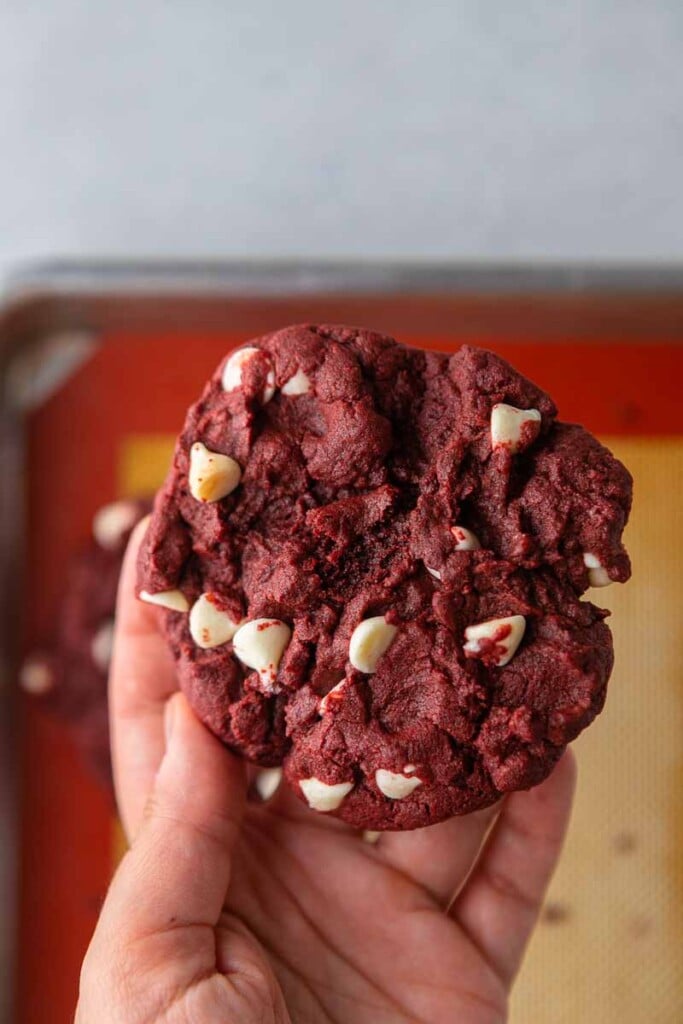 Hand holding CRUMBL white chip red velvet cookies