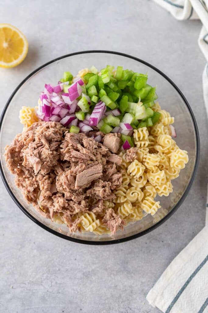 Pasta, tuna, onions, and celery in a bowl
