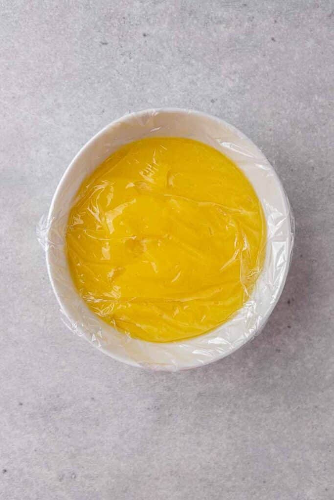 Lemon curd in a bowl with plastic wrap
