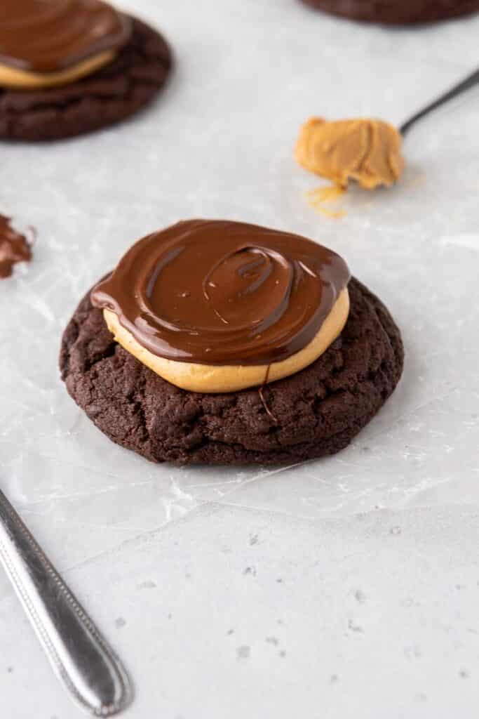 Crumbl peanut butter brownie cookie on parchment paper with a thick chocolate brownie cookie base topped with peanut butter and a chocolate ganache drizzle