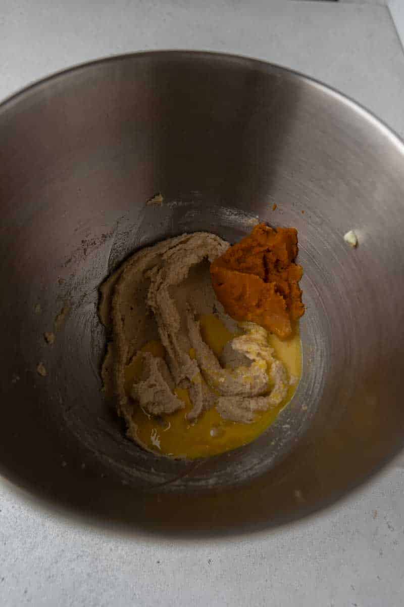 Butter, granulated sugar, and brown sugar creamed together in a bowl for pumpkin cookie dough.