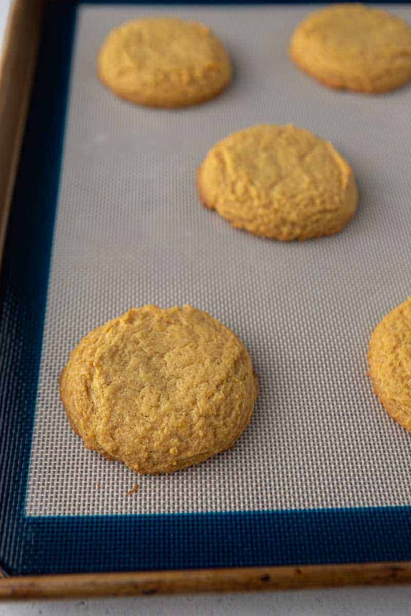 Baked pumpkin cookies cooling on a baking sheet.