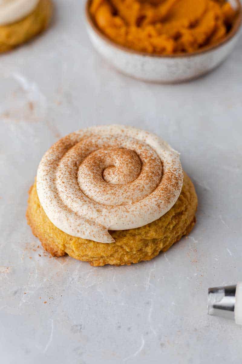 Pumpkin cookies topped with piped caramel cream cheese frosting.