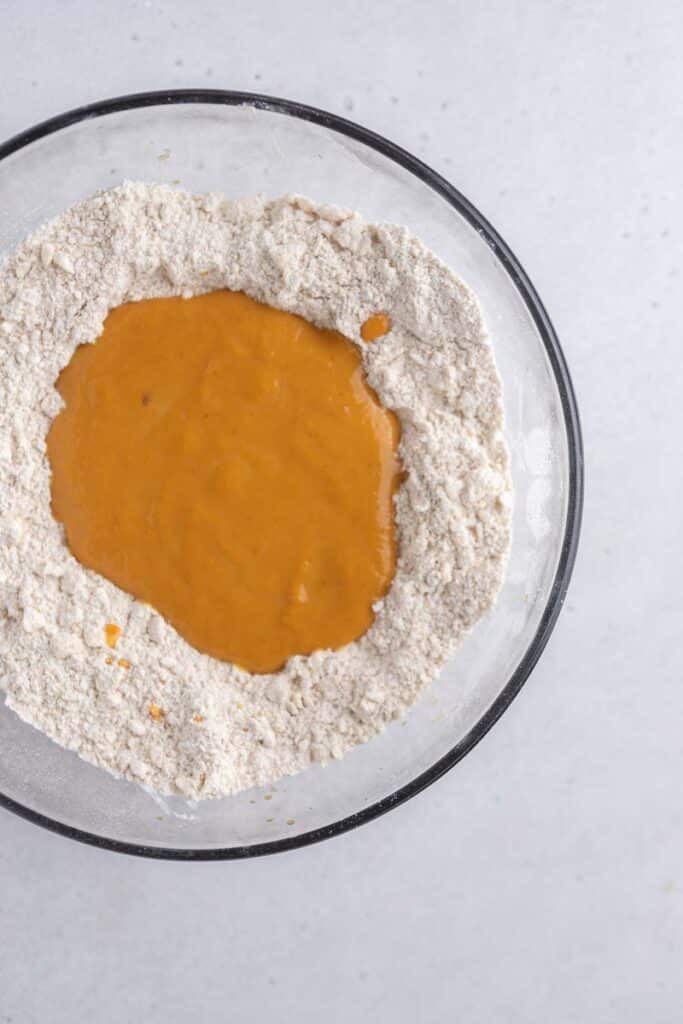 Wet pumpkin mixture with the dry ingredients in a bowl