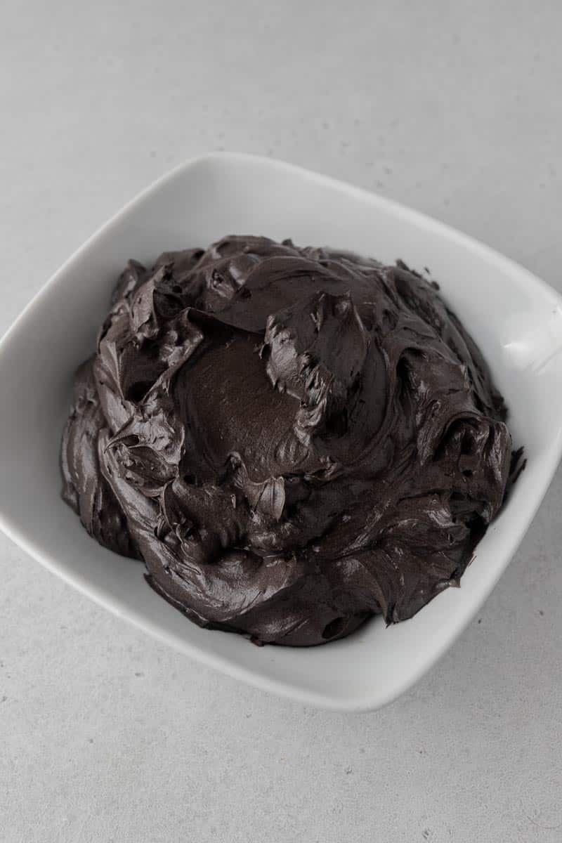 Dark black cocoa Swiss meringue buttercream in a white bowl.