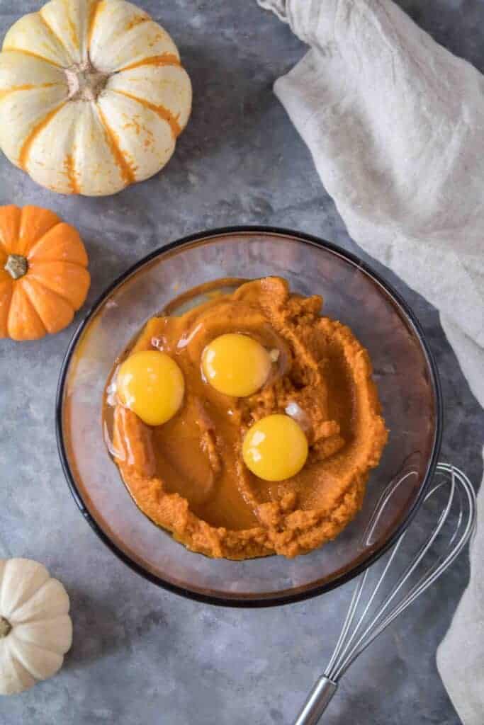 Pumpkin puree and three egg yolks in a glass bowl ready to be whisked together.