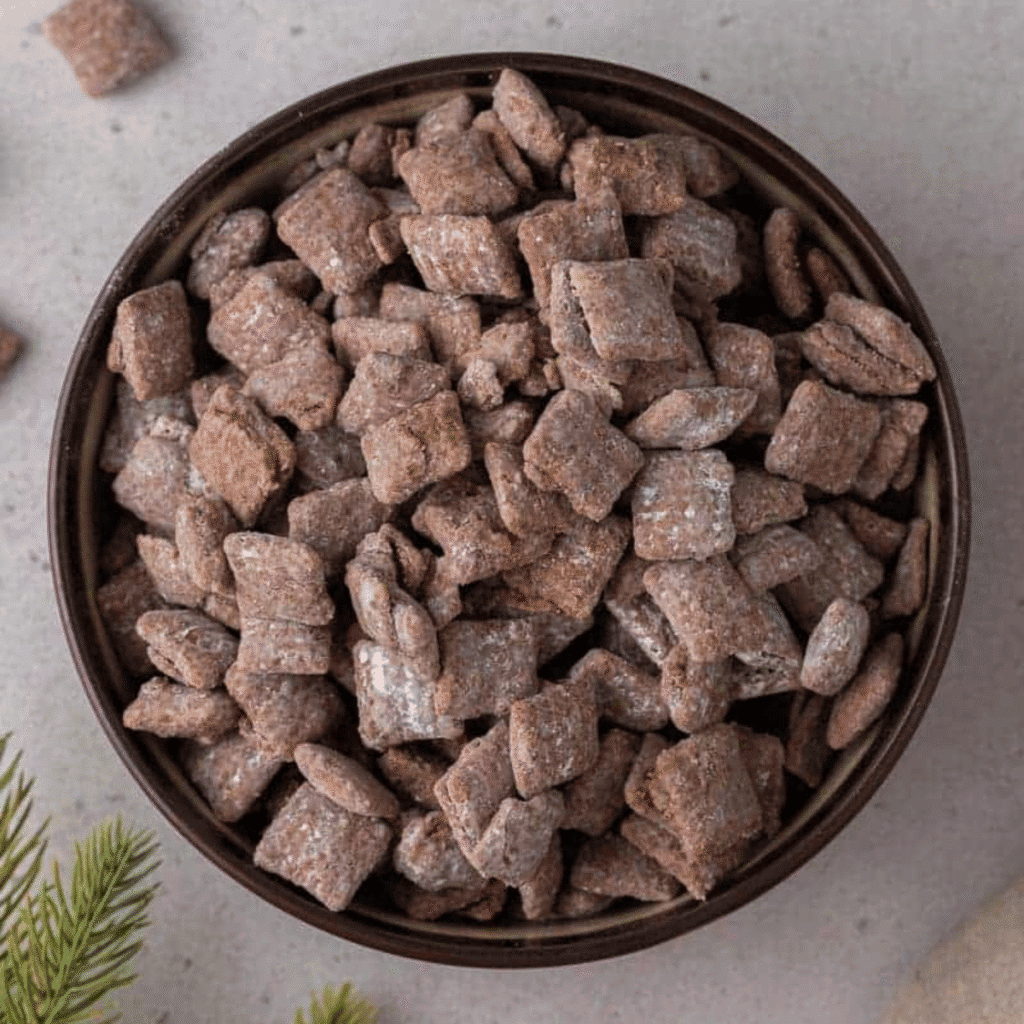 Bowl of classic muddy buddies (puppy chow) coated in powdered sugar and chocolate-peanut butter