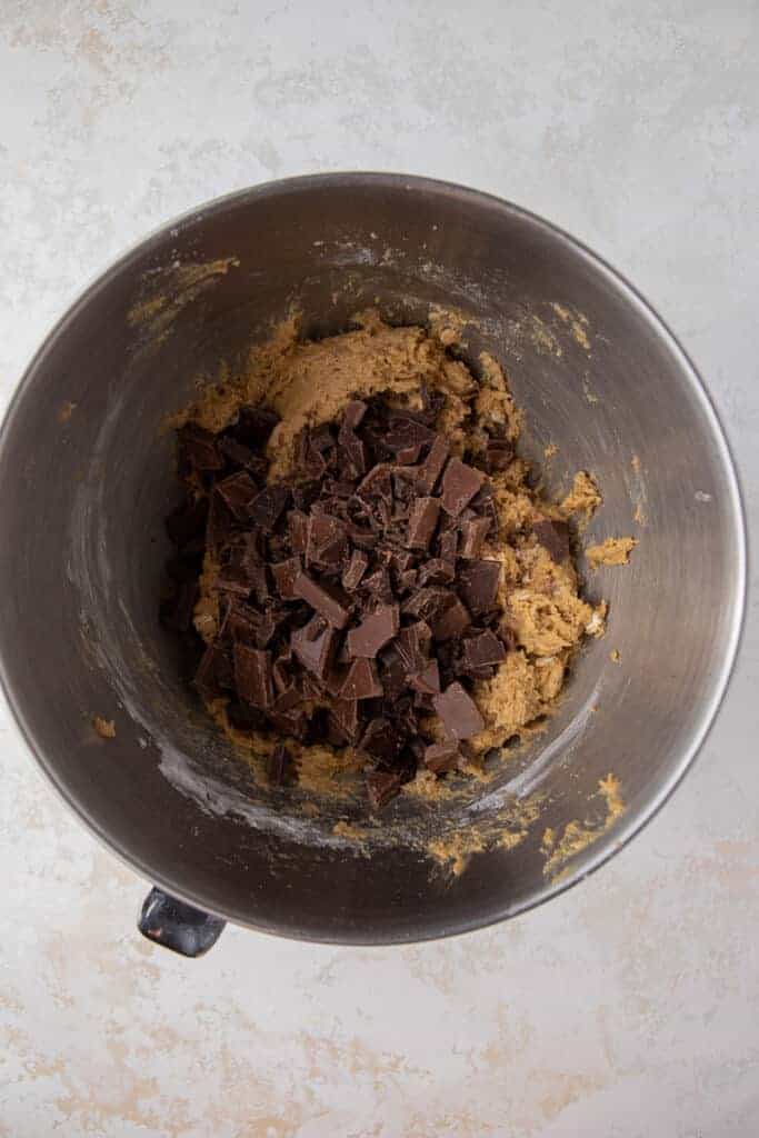 Finished Chick Fil A cookie dough in a bowl studded with roughly chopped chocolate bar pieces.