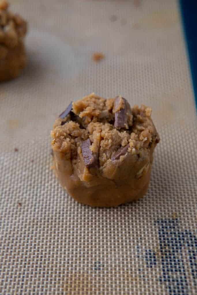 Dough balls on a baking sheet with ragged torn edges facing up after being split.