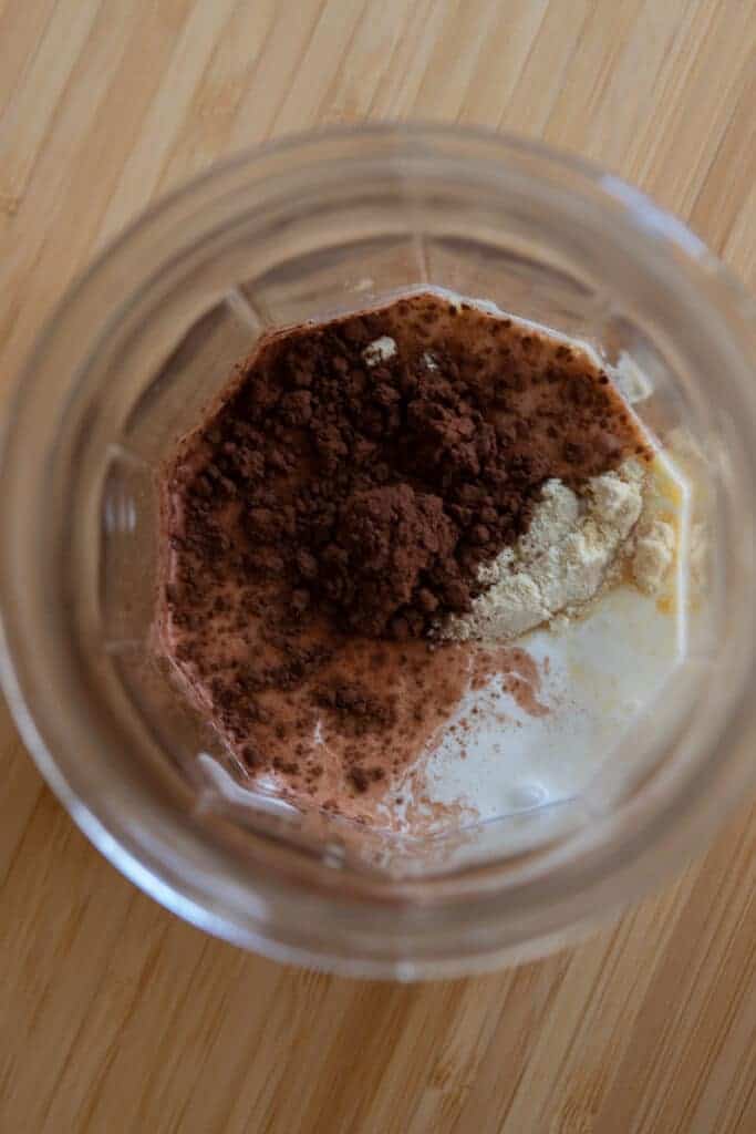 Chocolate cream ingredients on top of the liquid in a glass cup before being frothed.