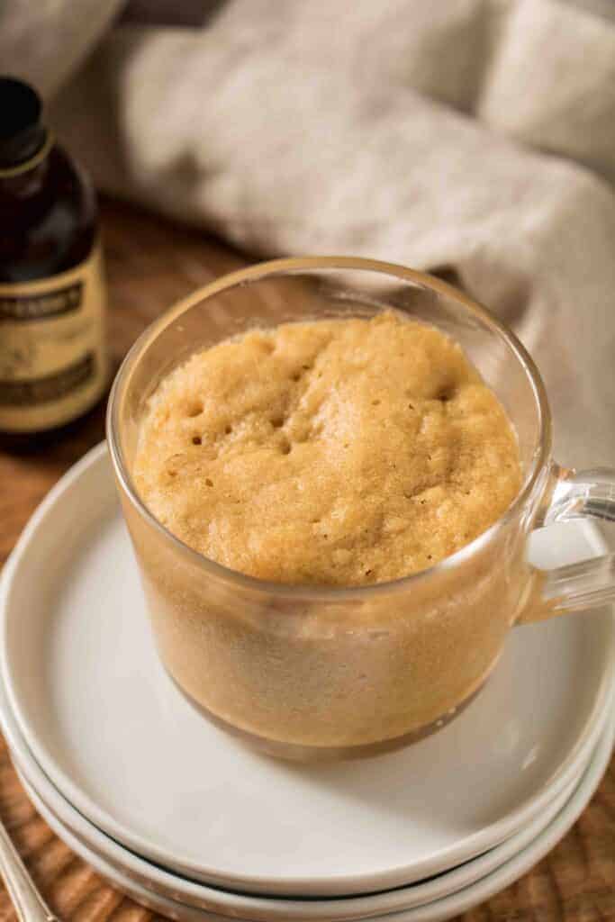 Close-up of peanut butter mug cake with whipped topping and crushed peanuts on a spoon.
