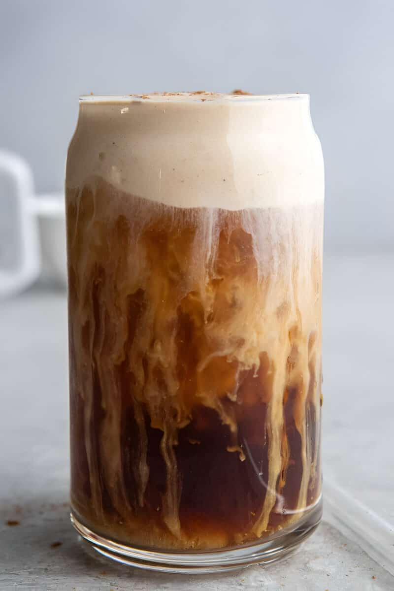 Pumpkin cream cold brew in a tall glass with thick pumpkin cold foam floating on top.