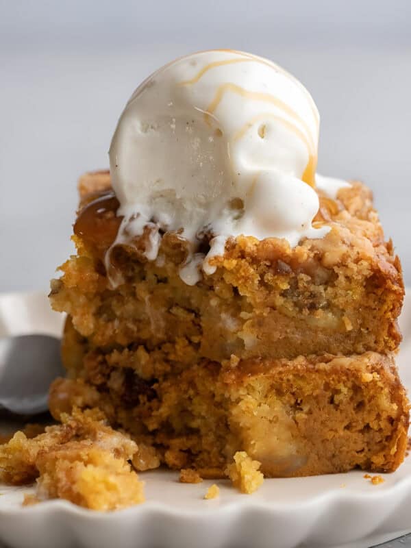 Squares of pumpkin crunch cake layered with custard and buttery pecan topping, served with ice cream.