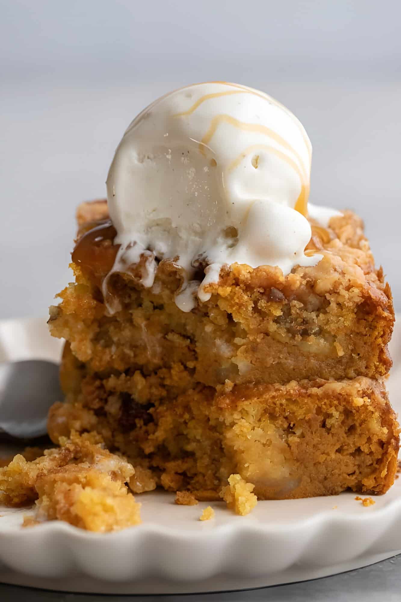 Squares of pumpkin crunch cake layered with custard and buttery pecan topping, served with ice cream.