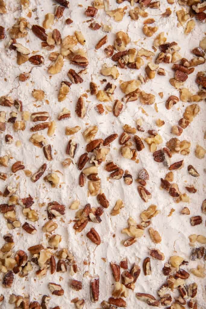 Dry yellow cake mix and chopped pecans spread evenly across the pumpkin layer in the pan.