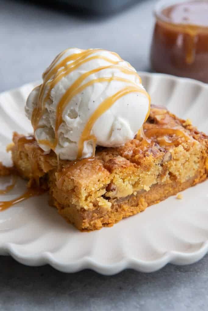 A warm square of pumpkin crunch cake served with vanilla ice cream and caramel sauce.