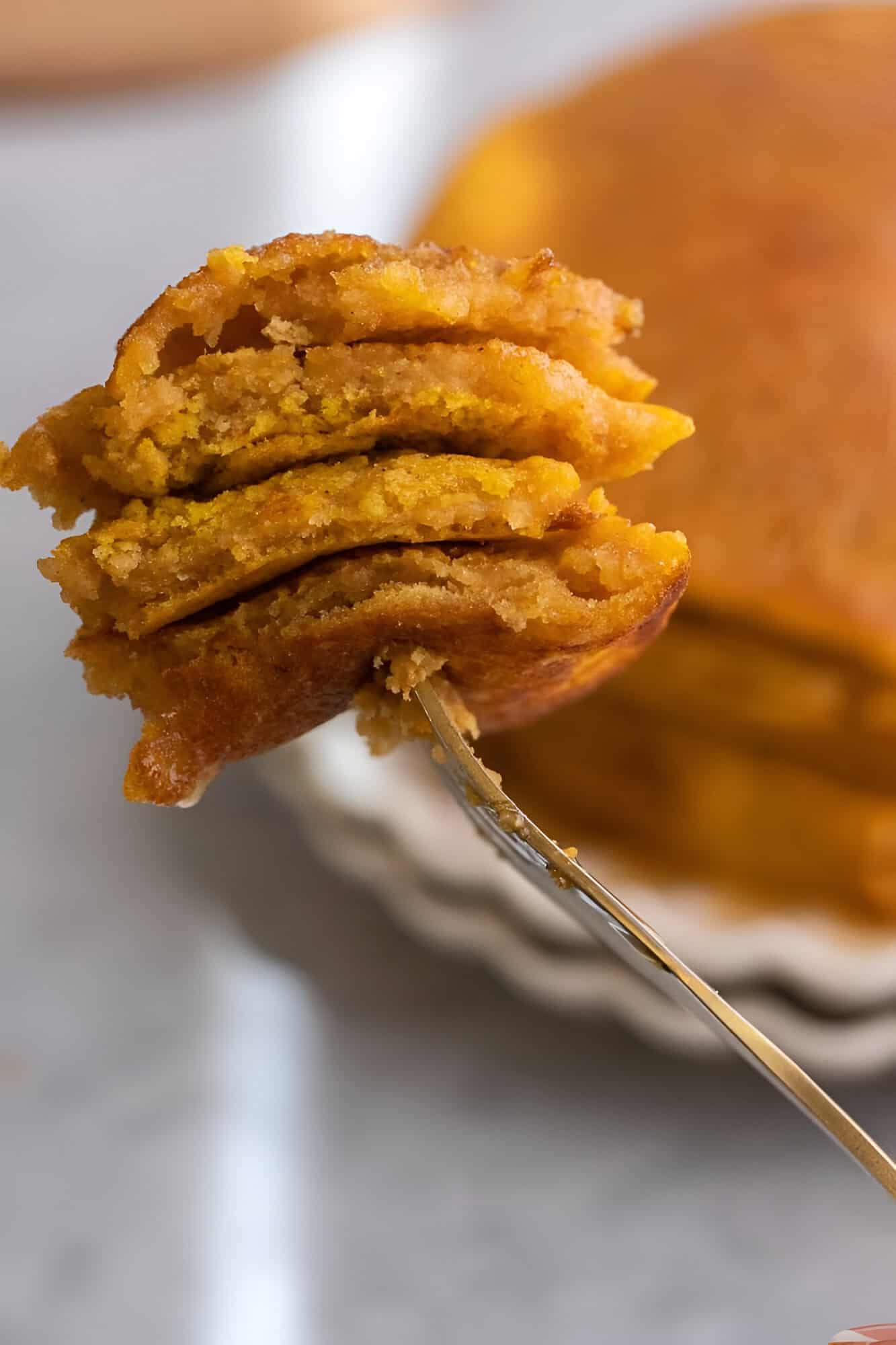 A tall stack of pumpkin pancakes in a fork made with pancake mix, dripping with maple syrup and butter.
