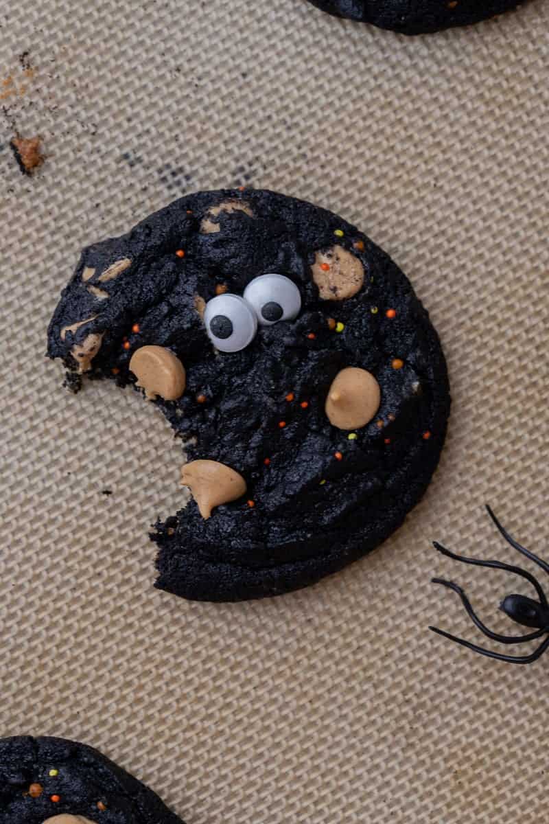 Baked black cocoa monster cookies topped with candy eyes and peanut butter chips.