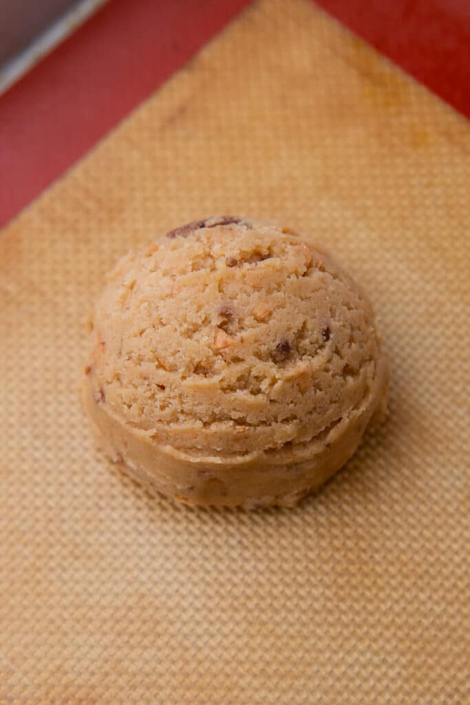 Scooped cookie dough ball on baking mat
