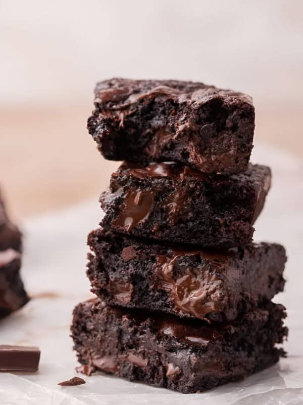 Three fudgy small batch brownies stacked to show the dense interior and melted chocolate pools.